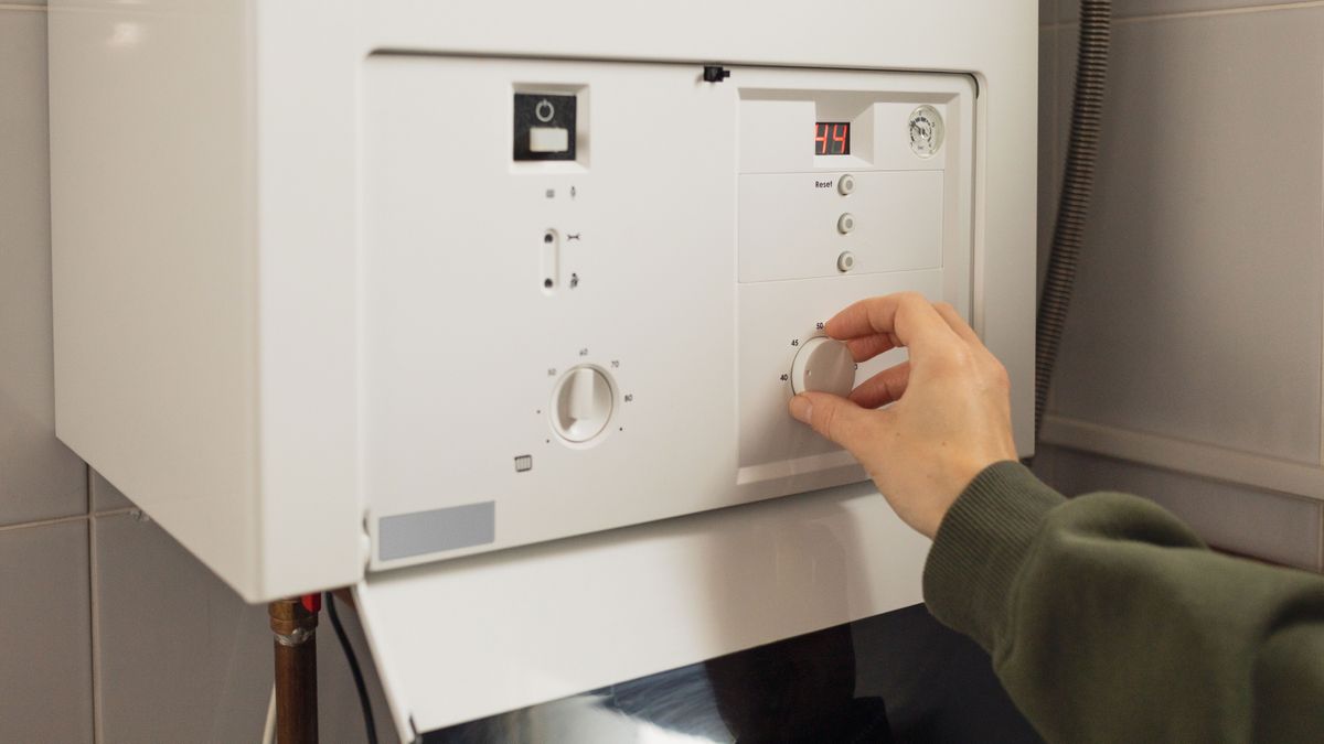 woman&#039;s hand adjusting gas boiler