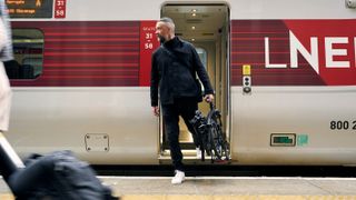 a photo of a man getting off a train carrying the Brompton Electric P Line