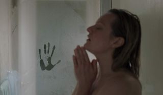 The Invisible Man puts his hand on the shower door, as Elizabeth Moss isn't looking