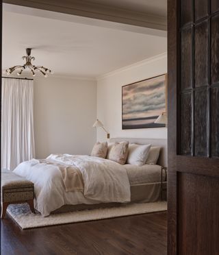 A bedroom with dark wood floor and white walls