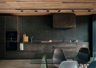 A stainless steel kitchen with dark elements all around it.