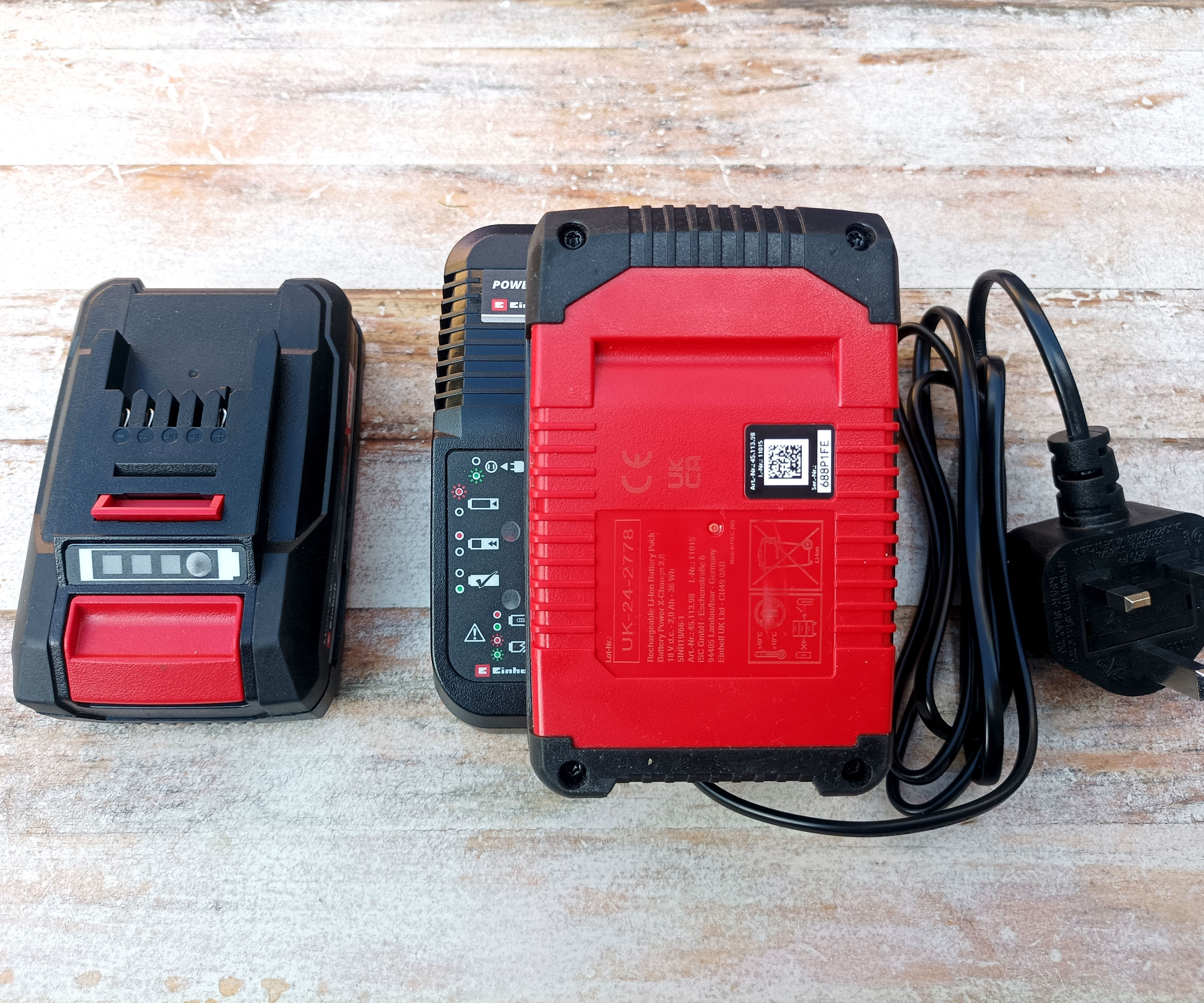 Einhell cordless drill battery charger and batteries on whitewashed wooden background