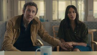 An upset Chris O'Dowd leans forward in disbelief as Rashida Jones holds his hand in Black Mirror S7 E1 - "Common People."