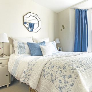 white bedroom with bed and wall mirror