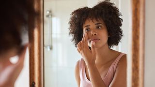 woman applying face cream in mirror