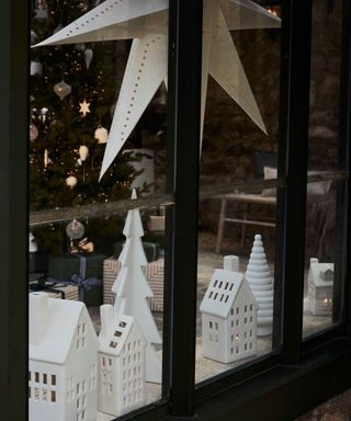 Ceramic house ornaments and paper star decoration on display in window