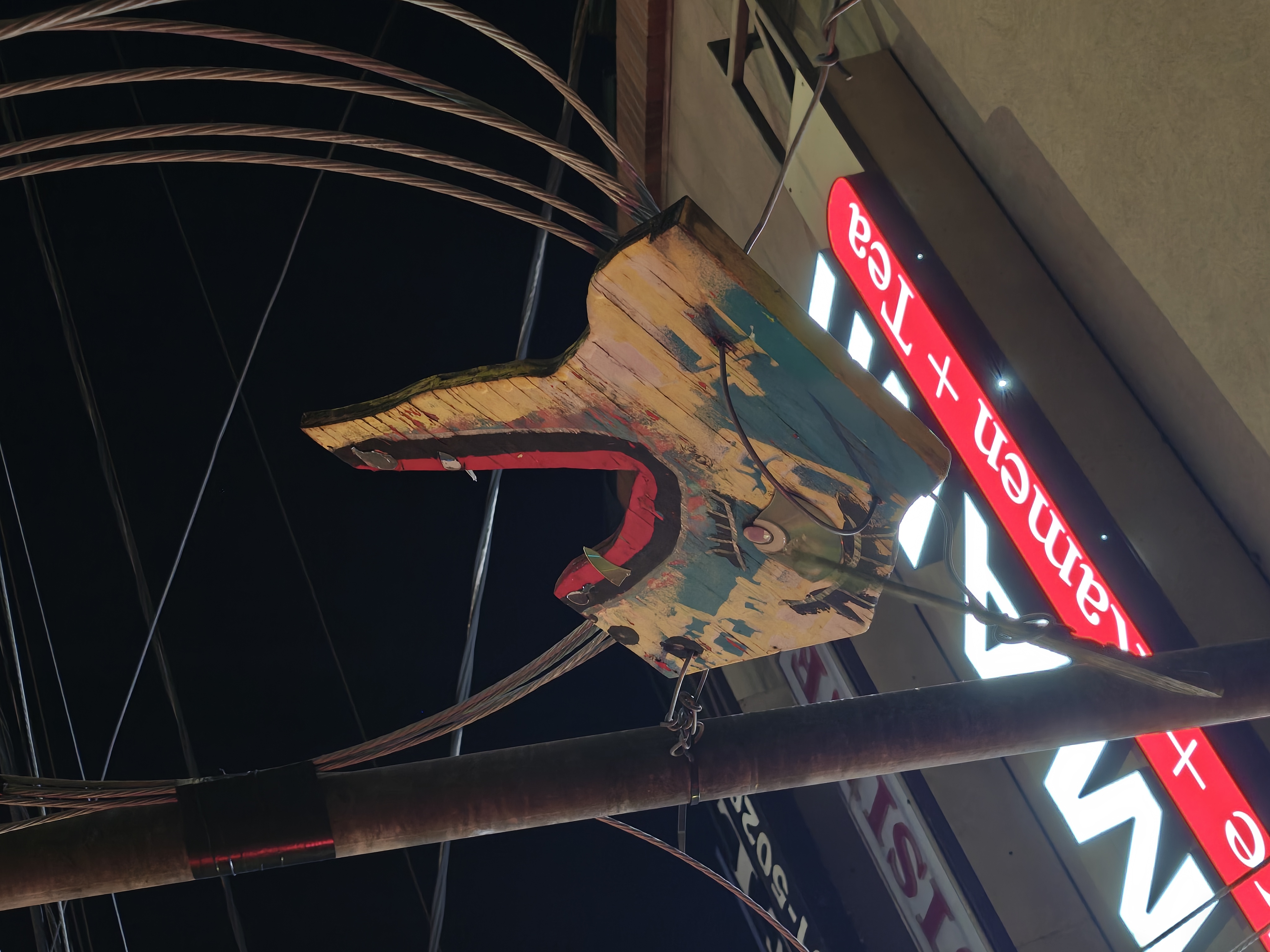 A carved wooden animal face hanging from a pole
