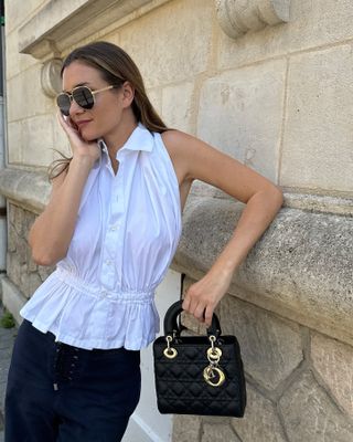 French woman wearing a white top and carrying a Dior bag