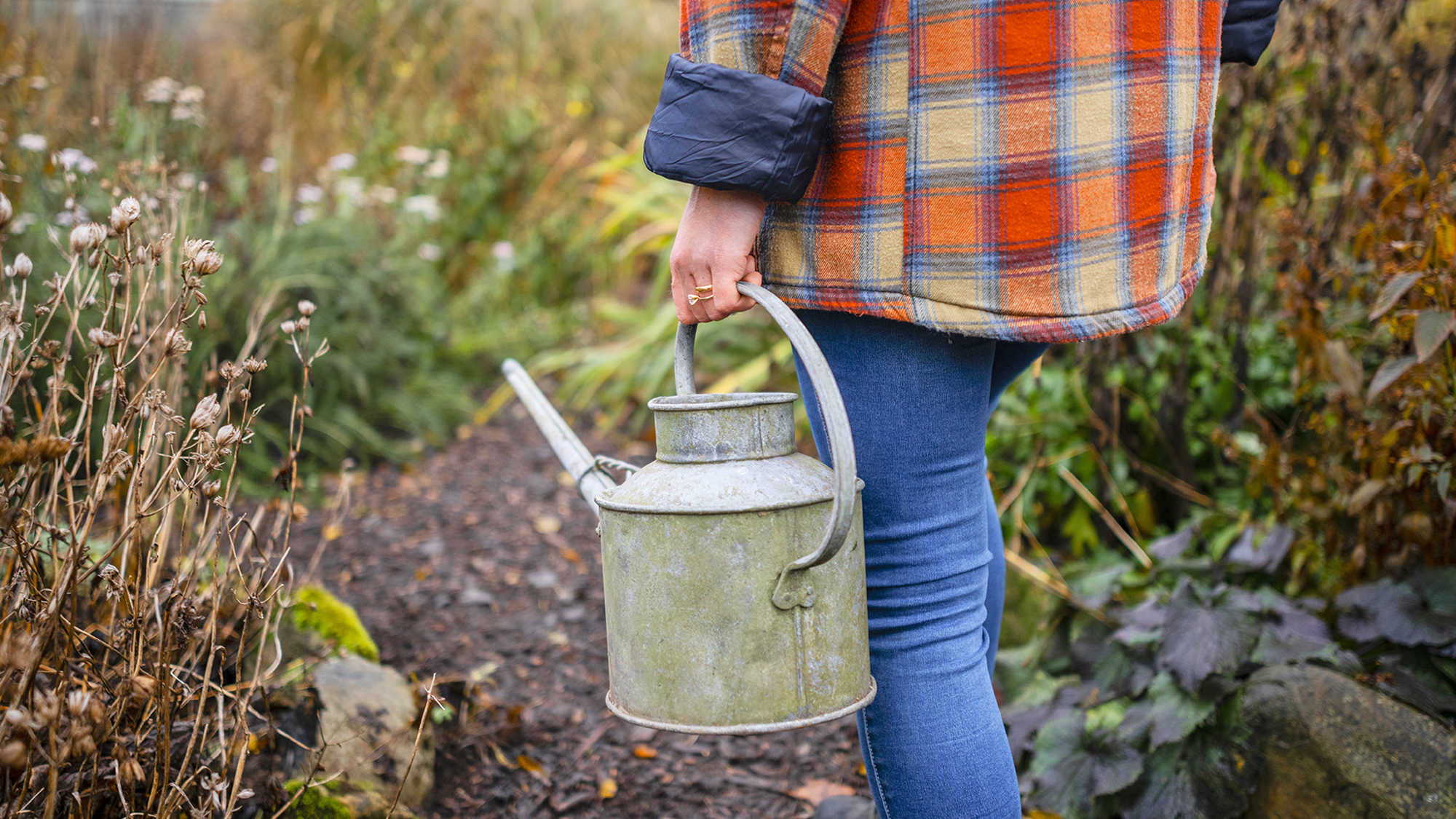 Low angle view of a woman carrying a watering can ready to tend to her crops.