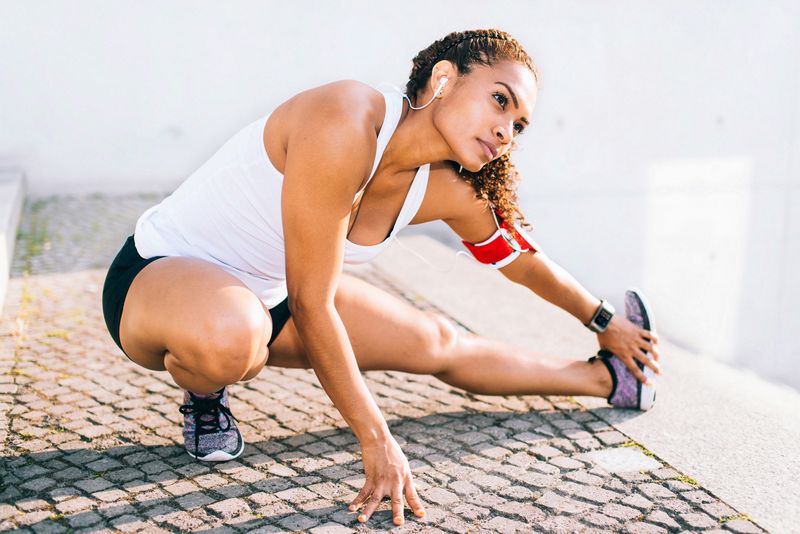 A woman crouching down to stretch her legs