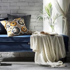 living area with brick wall and blue sofa and pillow