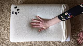 A hand pressing down on the Panda Memory Foam Bamboo Pillow