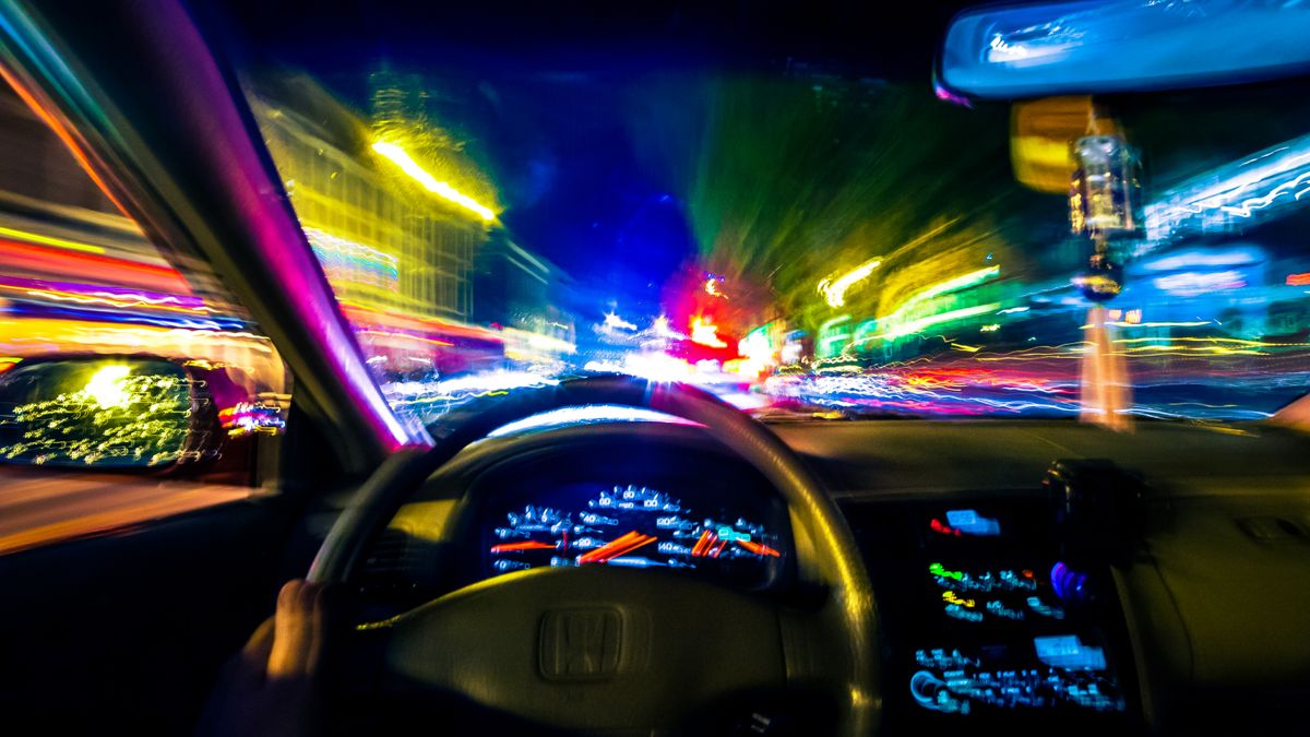 Point of view behind the wheel of a car with lights blurred as if driving very fast.