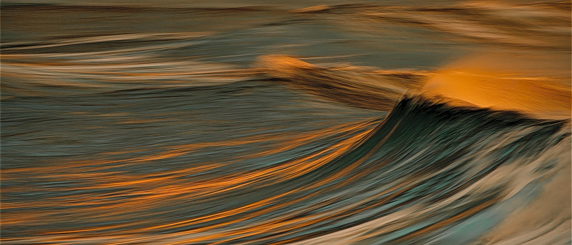 A serene, horizontal abstract depicting the long-exposure motion of an ocean wave, with deep teal shadows and a crest illuminated by a warm, golden glow.