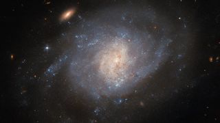 a blue and white spiral galaxy in the black of space