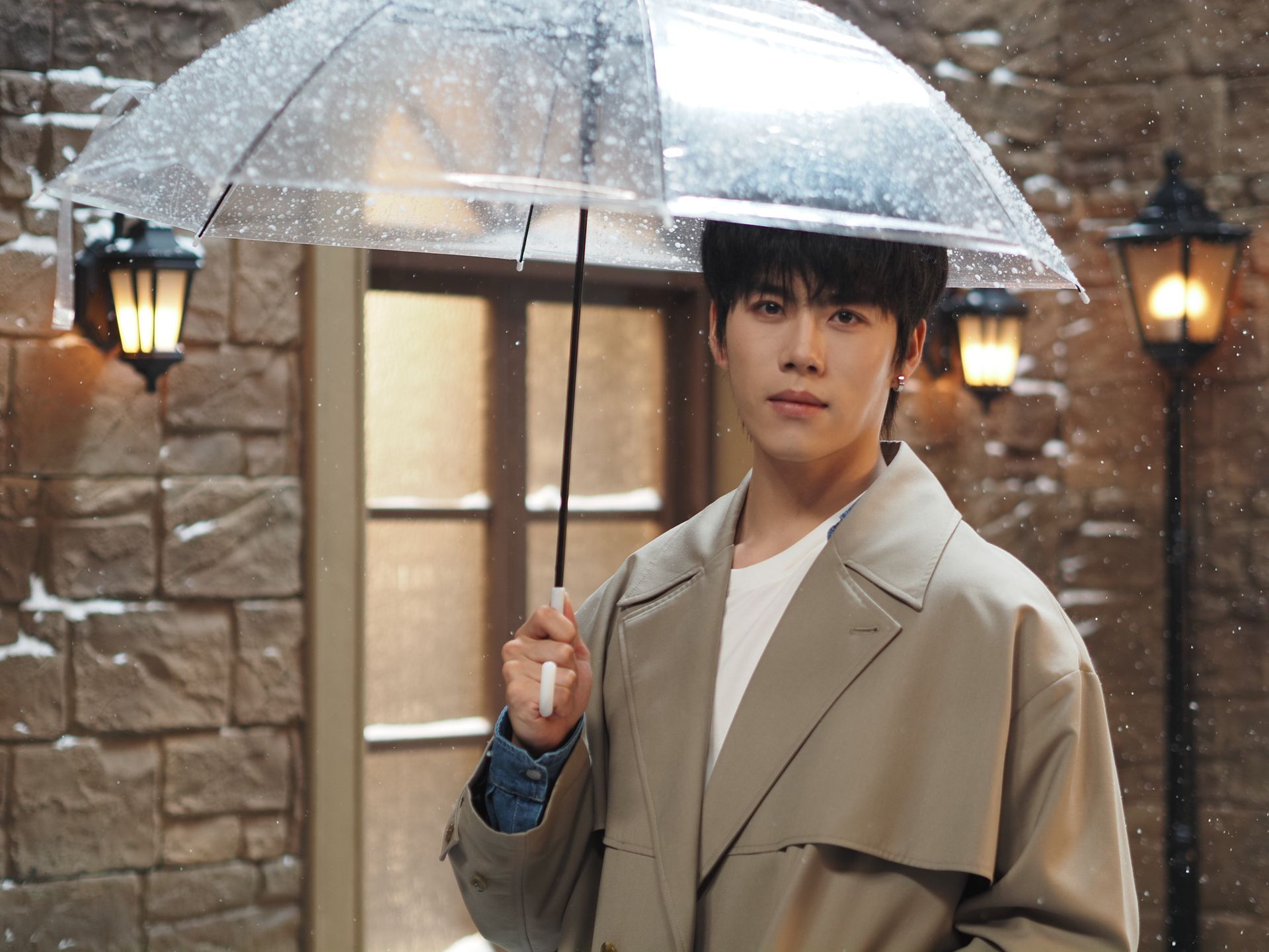  Male model in overcoat holding a clear umbrella, there's a snowy old town studio backdrop