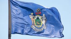 Maine flag flying in the sky for Maine state tax guide