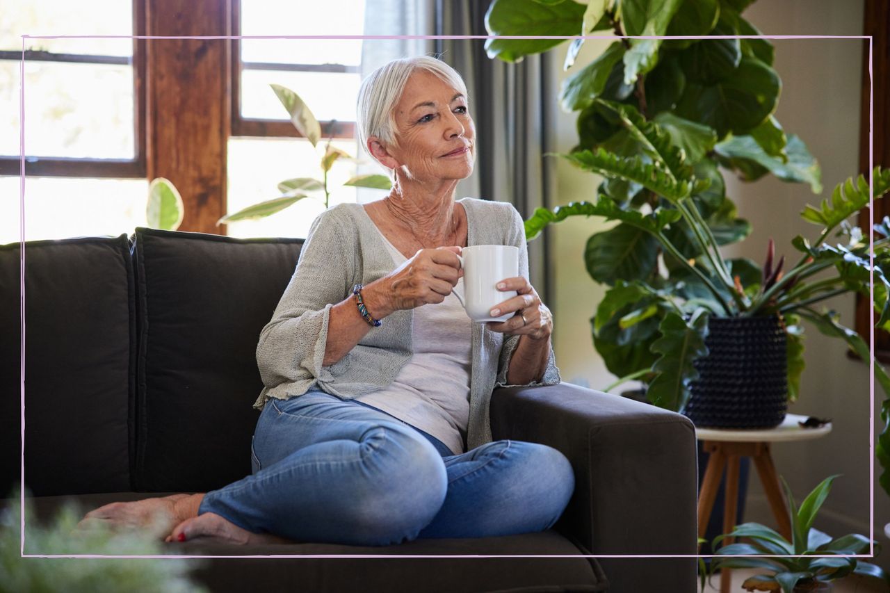 Woman sat alone on her sofa having coffee