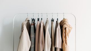 collection of neutral-colored clothes on hangers on a clothes rail