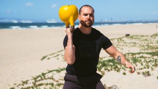 Man performing a bottoms-up kettlebell grip with right arm raised