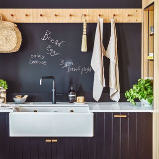 close up of black kitchen with white sink and tea towel hanging on peg rail