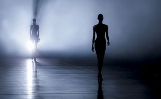 Image of a models on a catwalk under a dark/blue shadowy light