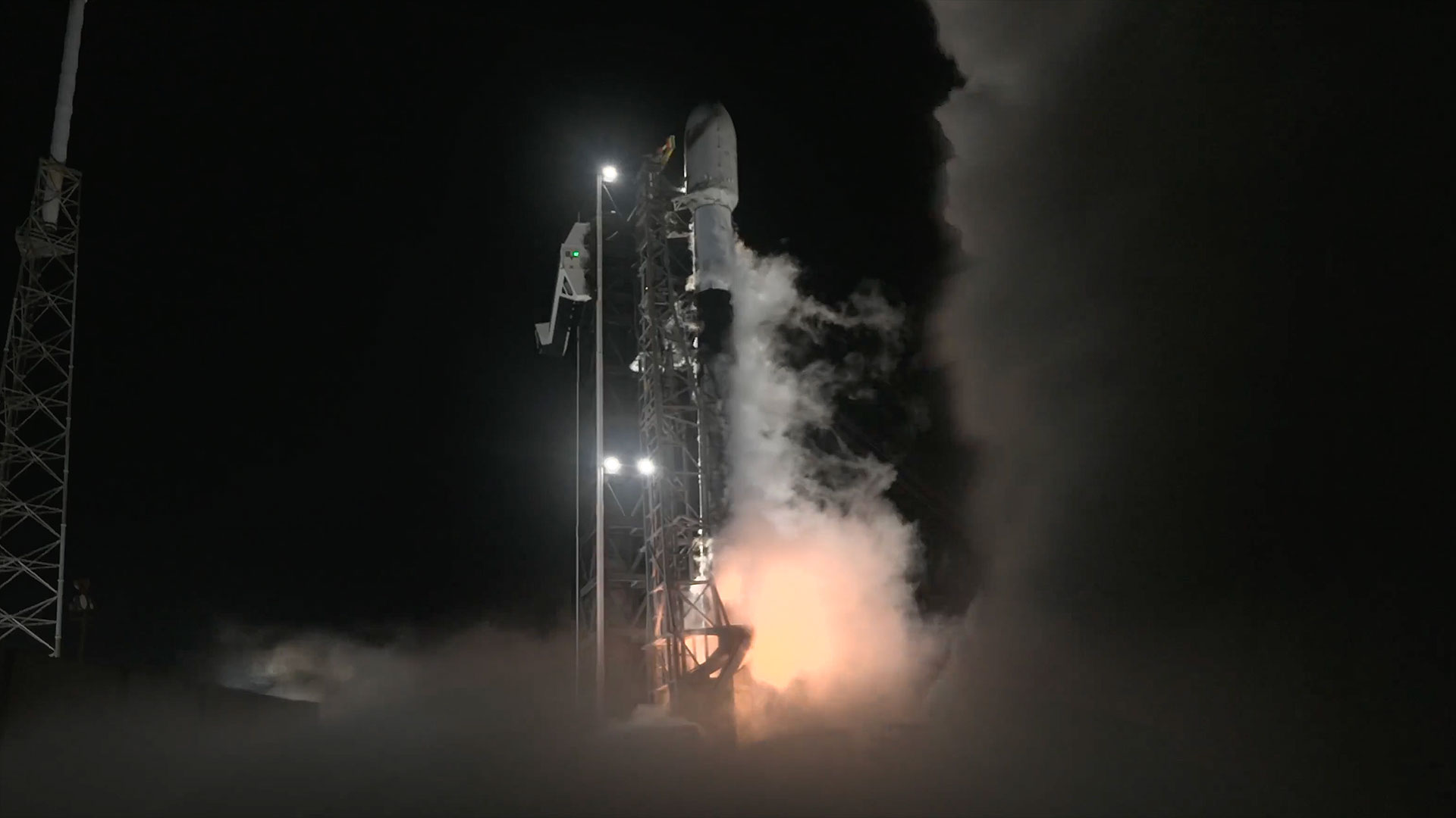 a white and black rocket lifts off into the night sky.
