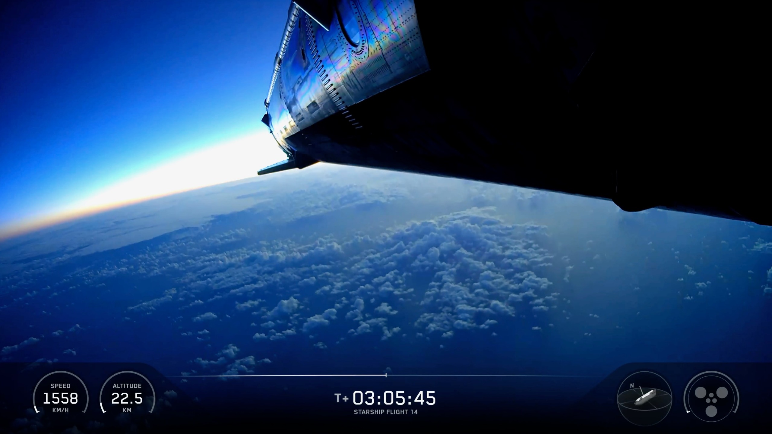 a large spacecraft descends through Earth's atmosphere over a sea speckled with clouds