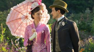 Maud holds a parasol while walking in a garden with Oscar