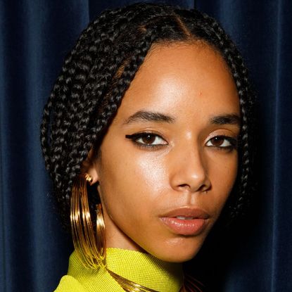 Best cleanser for oily skin - black model wearing neon green top and gold hoops - getty1699161488 