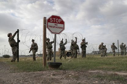U.S. soliders set up barbed wire at a Border Patrol facility in Donna, Texas