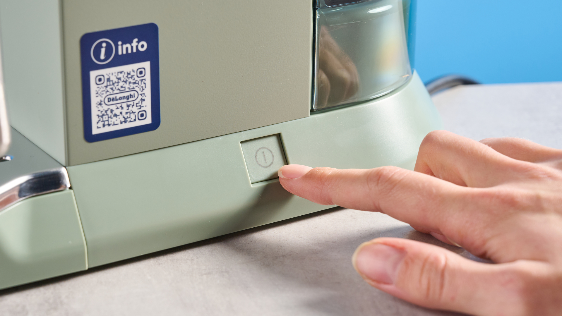 DeLonghi Dedica Duo in the green colorway with accessories photographed on a blue background.