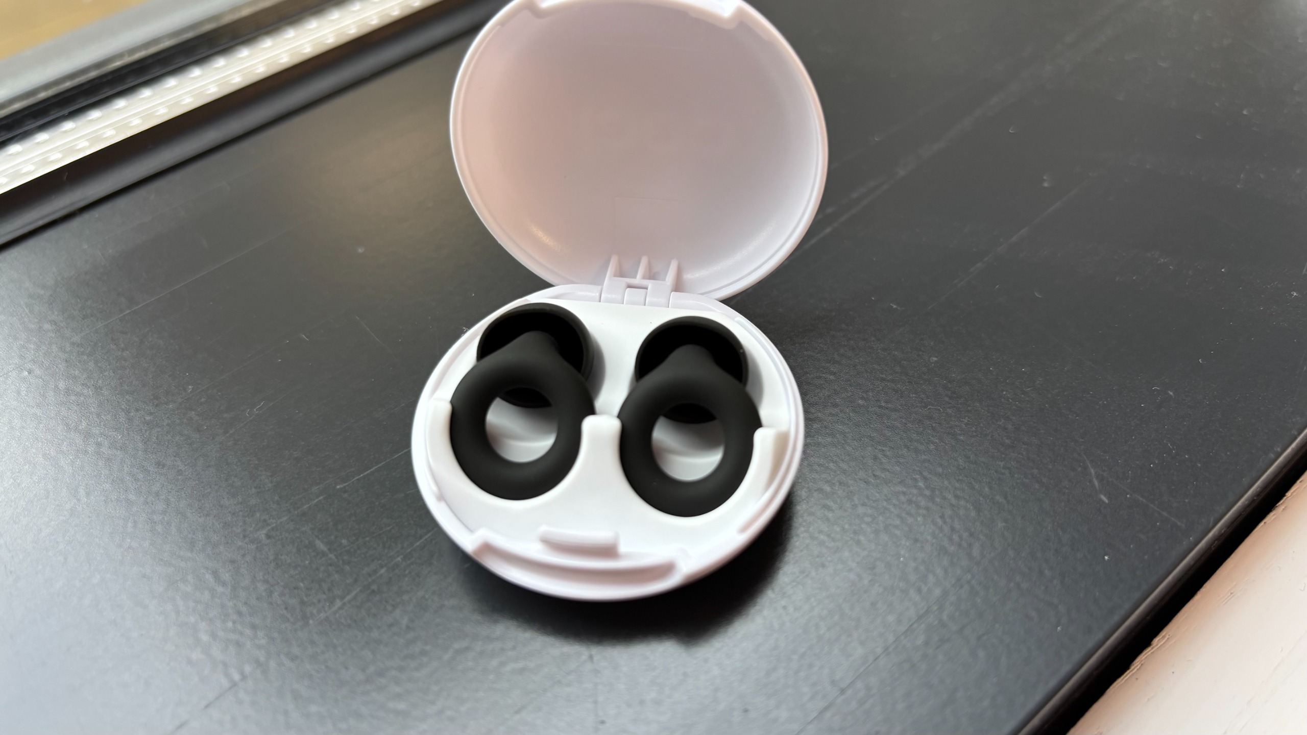 The Loop Quiet 2 Earplugs in their travel case on a window sill.