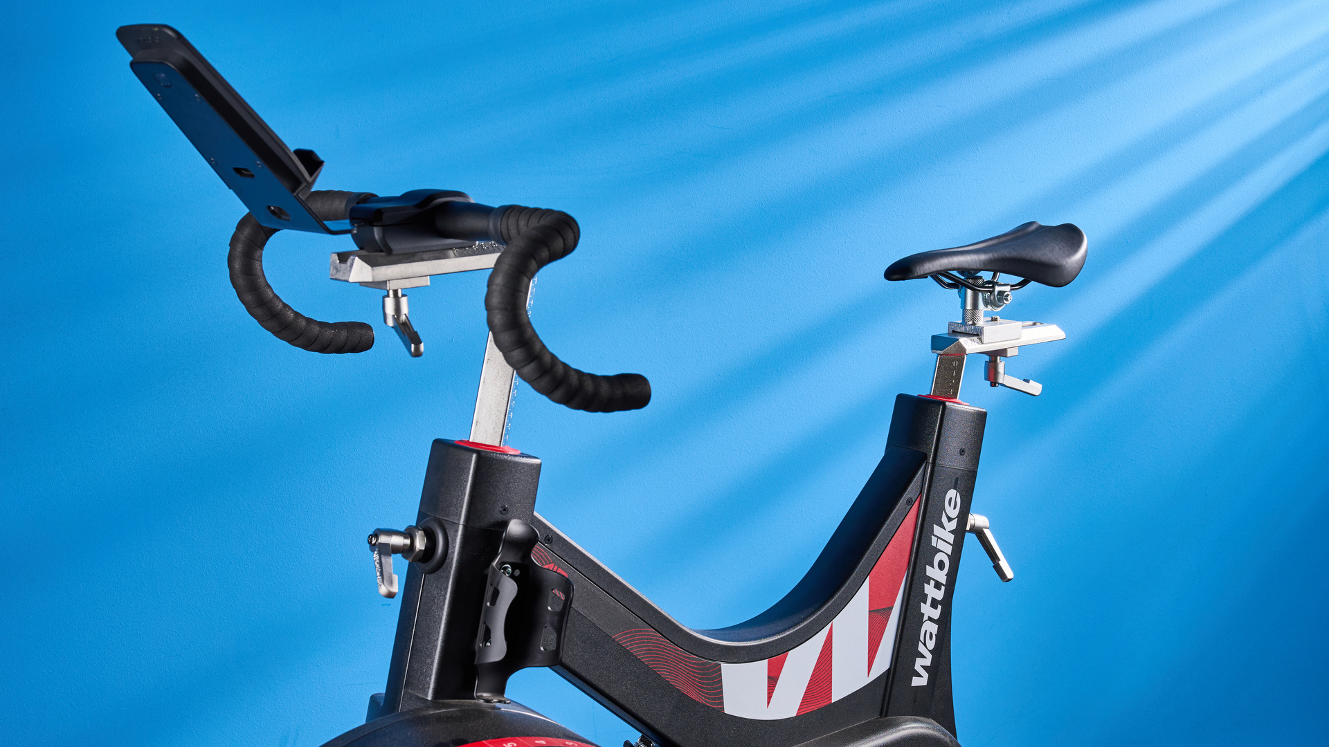 the wattbike air with a black and white front wheel, adjustable seat, and phone holder with app compatibility