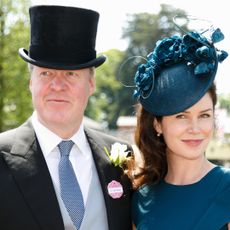 Charles Spencer wearing a top hat and suit standing next to Karen Spencer in a blue dress and matching hat with flowers