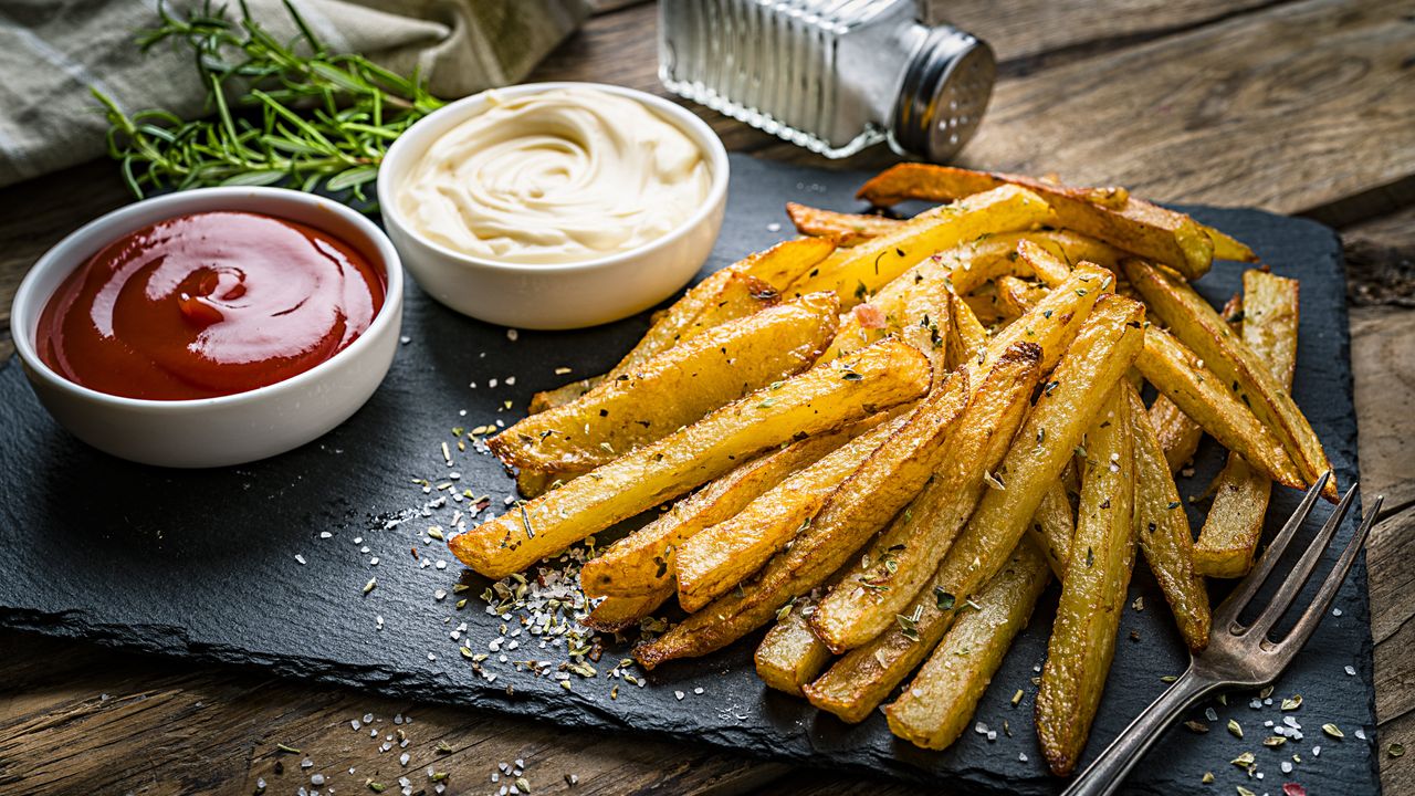 Homemade chips on slate board with ketchup and mayonnaise