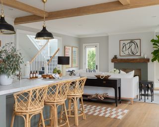 A modern farmhouse-style, open-plan kitchen and dining area with bamboo bar stools and white sofa