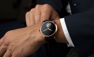 minimalist watch on man's wrist, in black, by H Moser