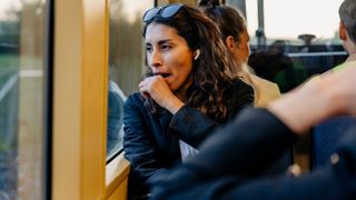 A tired woman on a train looking out of the window and yawning