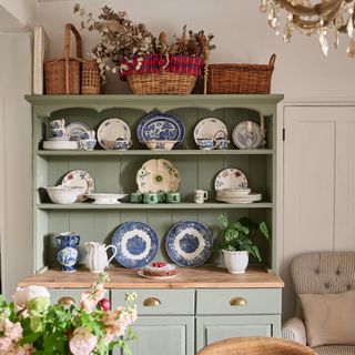 pal green painted vintage kitchen dresser with displays of vintage china and baskets