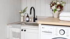 Bright neutral laundry room with styled close-up of sink, counter and top of washer