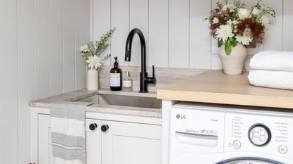 Bright neutral laundry room with styled close-up of sink, counter and top of washer