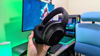 A Razer Barracuda X Chroma headset held in the hand with its RGB lighting disabled.