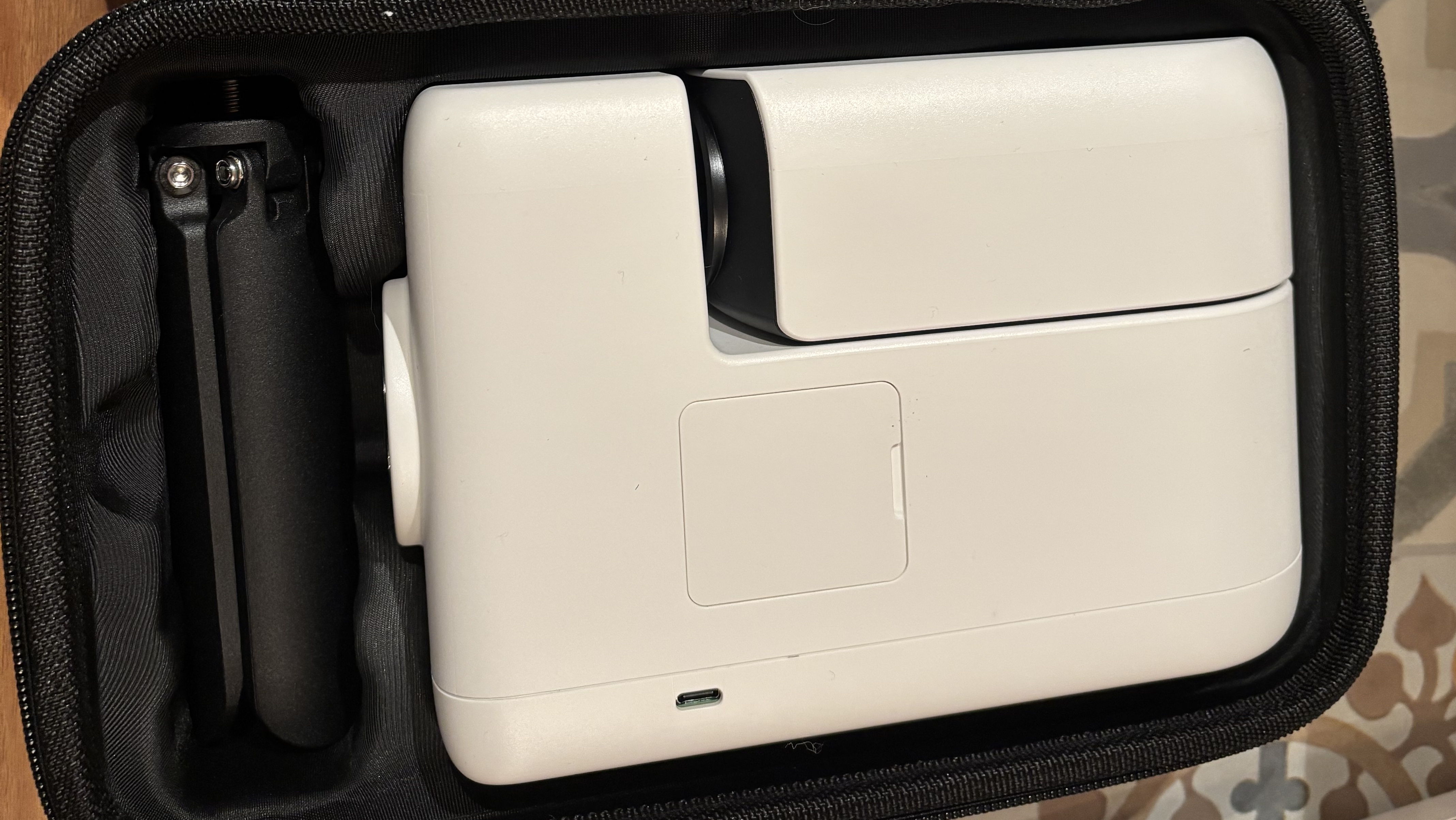 A white smart telescope is folded up and its tripod is too, all placed inside a carry case.