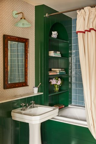 A small colourful bathroom with frilled bath curtain, blue wall tiles and glossy green shelving