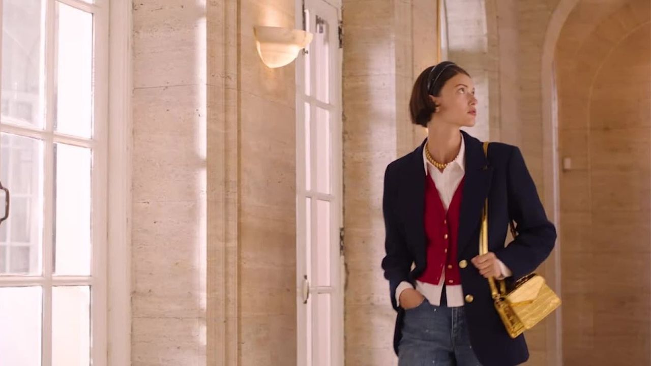 woman with a navy blue blazer, red vest, and yellow handbag