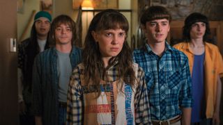 Stranger Things Millie Bobby Brown as Eleven intensely staring with Noah Schnapp as Will and other behind her on Strangers Things season 4