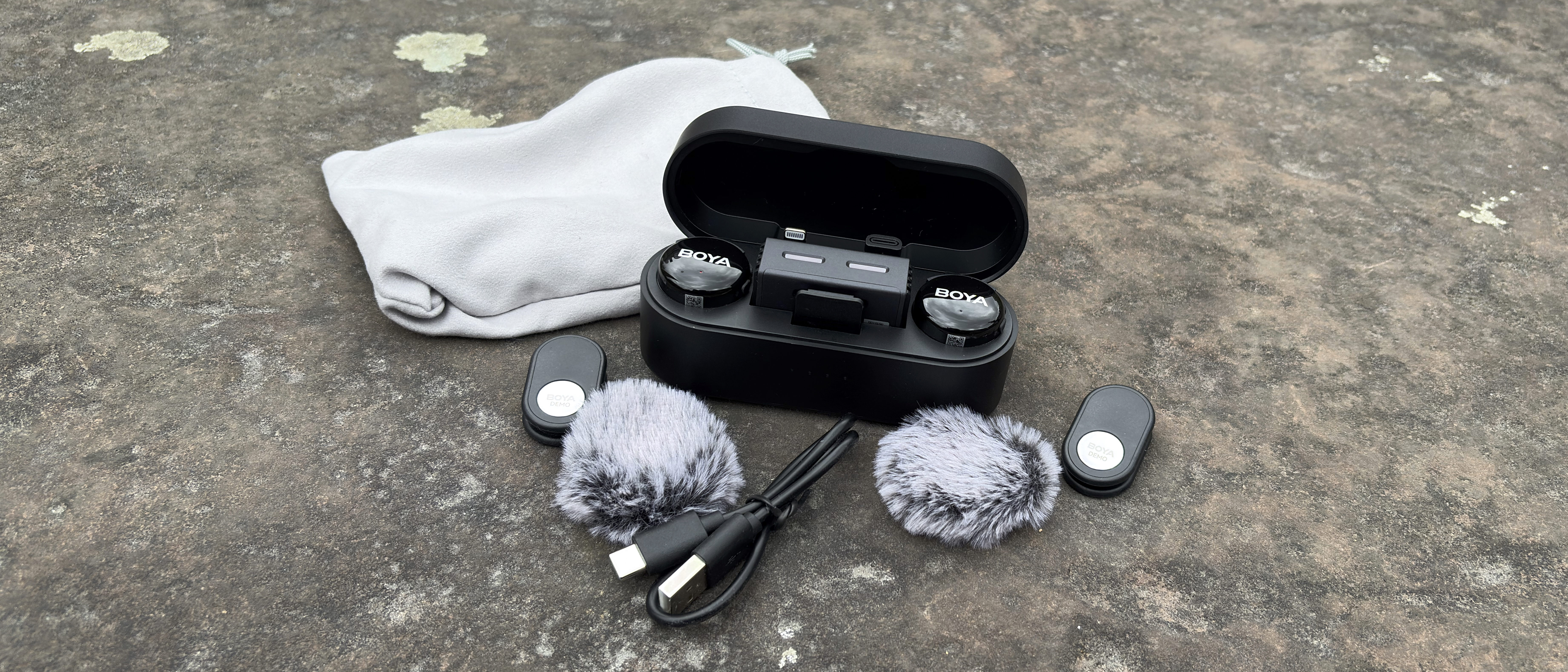 Shot of the Boyalink 3 kit, including wireless mics and receiver in their charging carry case, clips, a USB-C charging cable and two windshields