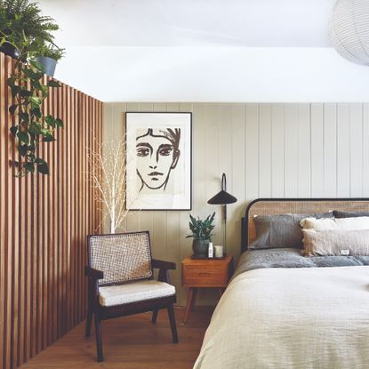 A bedroom with two different types of wall panelling and wooden floors