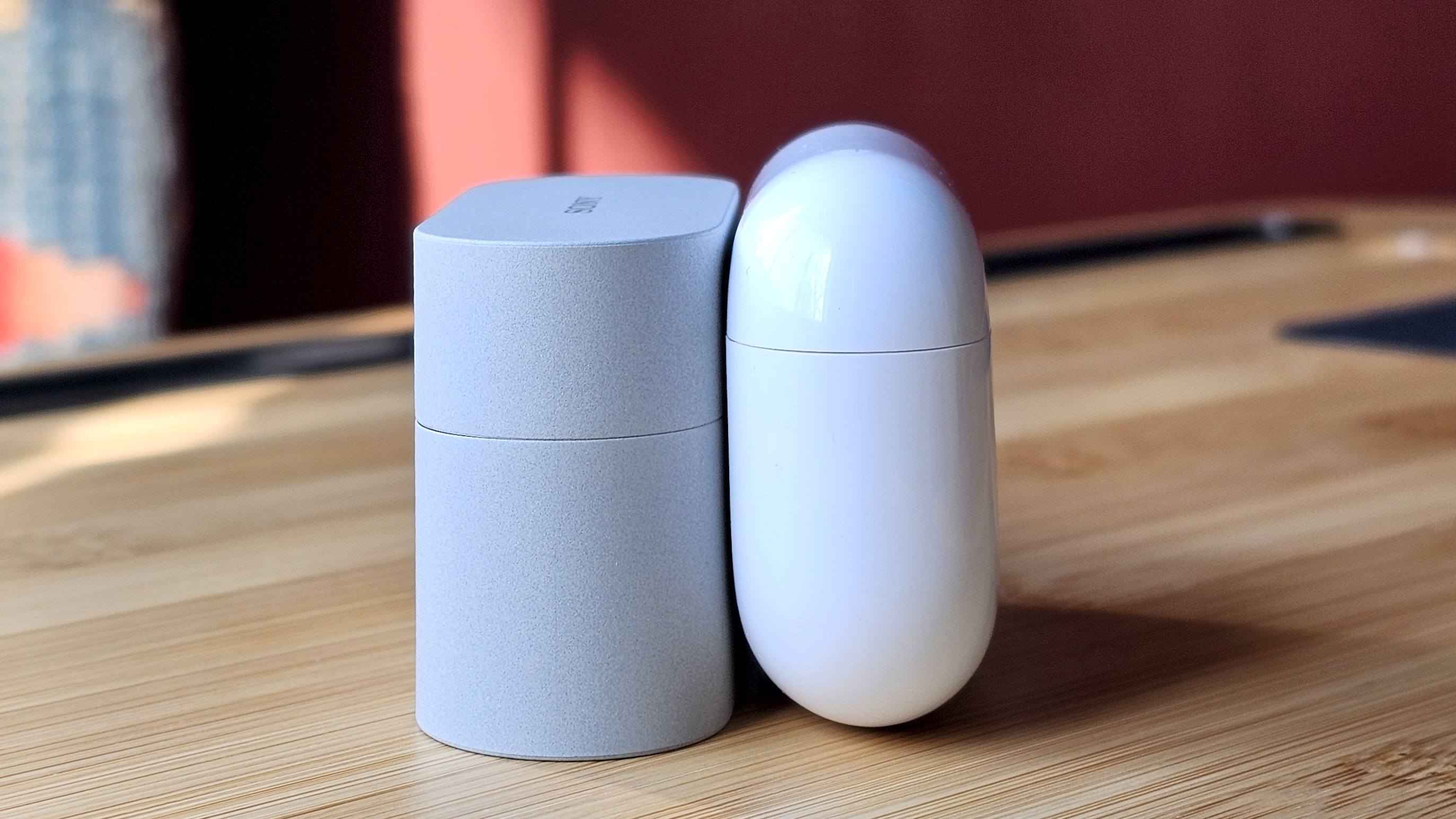 Sony WF-1000XM6 earbuds next to the Apple AirPods Pro 3, on a wooden table, in a versus-style format